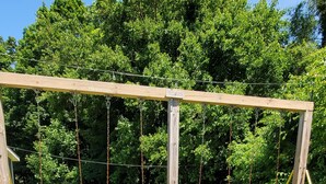 A wooden swing set with four swings in a grassy backyard.