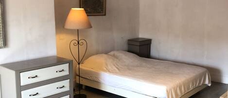 Un dormitorio con una cama, un tocador, una lámpara y un cuadro en la pared.