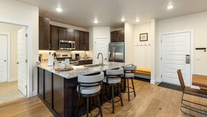 A modern kitchen with dark wooden cabinets, stainless steel appliances, and a granite countertop.
