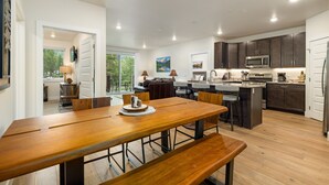 A modern kitchen with dark cabinets, a wooden dining table, and a built-in island with a microwave.