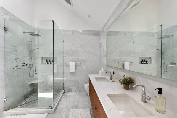 A modern bathroom with a glass-enclosed shower, a large mirror, and a vanity with a sink and countertop. - Fantastic Home in Wicker Park (Chicago)