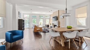 A spacious living area with a wooden dining table, white chairs, a blue armchair, and a fireplace. - Fantastic Home in Wicker Park (Chicago)