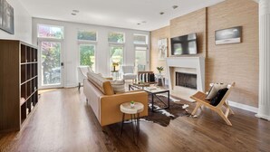 A spacious living room with a fireplace, large windows, and a TV mounted on the wall. - Fantastic Home in Wicker Park (Chicago)
