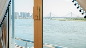 A view from a window overlooking a river with a bridge and buildings in the distance. - Nile Transport Hotel (Shubra al Khaymah)
