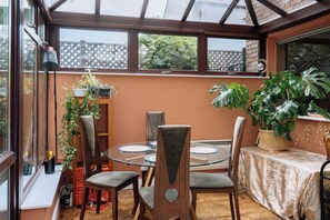 A conservatory with a glass table and chairs, surrounded by potted plants and a view of the outside. - Peaceful + Charming 2 BR Home in Rathmines, Dublin (Dublin 6)
