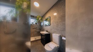 A modern bathroom with a toilet, sink, and shower.