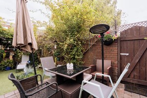 An outdoor patio with a table and chairs, surrounded by a garden and a wooden fence. - Peaceful + Charming 2 BR Home in Rathmines, Dublin (Dublin 6)