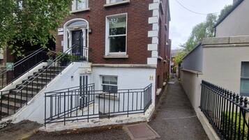 A narrow street with a staircase leading to a building with a white and red facade.