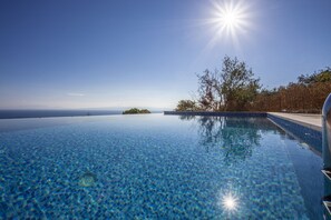 A clear blue infinity pool with a view of the ocean and a clear sky. - Olea Skopelos villa with breathtaking sea view and swimming pool (Panormos)