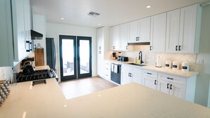 A modern kitchen with white cabinets, a large island, and a view through the glass doors. - ✻ Scottsdale ✻ OASIS W/ POOL & GOLF, 4 Bed 2 Bath (Scottsdale)