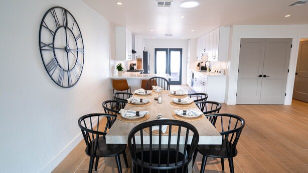 A modern kitchen with white cabinets, a large clock, and a dining area with a wooden table set for six. - ✻ Scottsdale ✻ OASIS W/ POOL & GOLF, 4 Bed 2 Bath (Scottsdale)