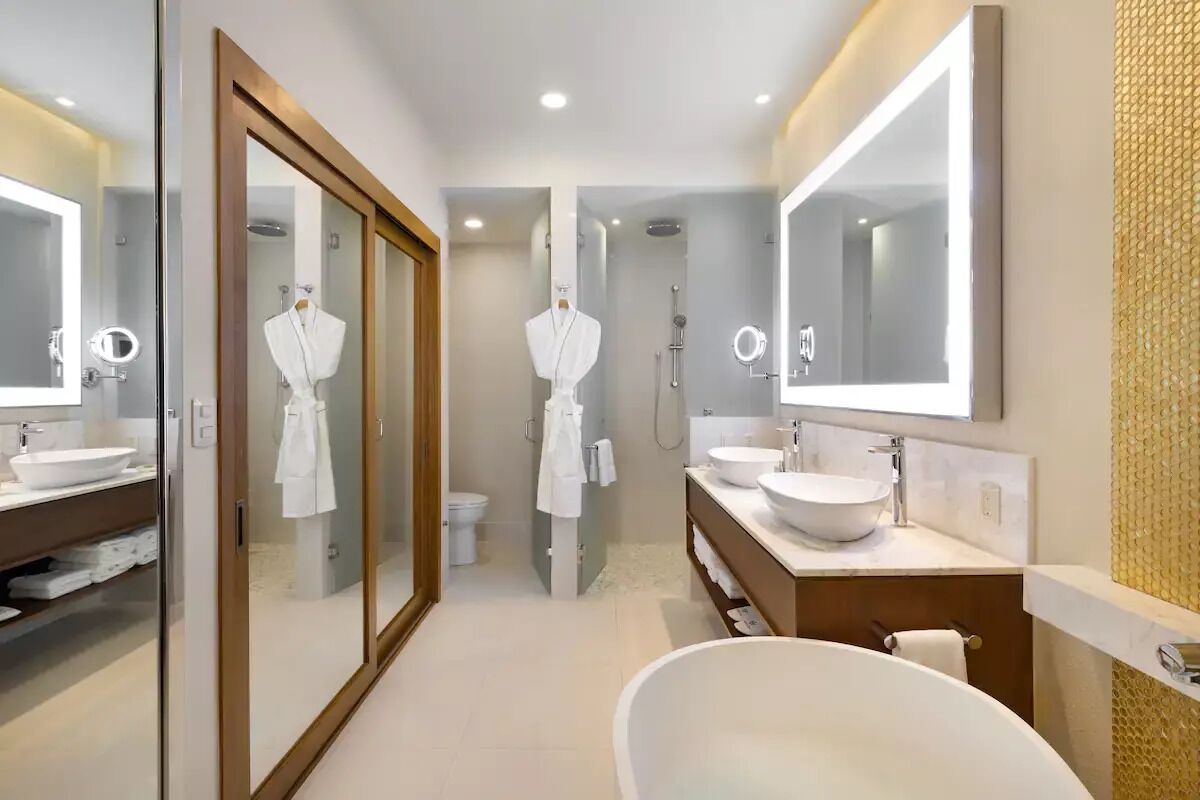 Une salle de bain moderne avec un grand miroir, deux lavabos, une baignoire et une douche.