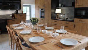 Una cocina moderna con armarios de madera, una larga mesa de comedor preparada para seis personas y un horno empotrado.