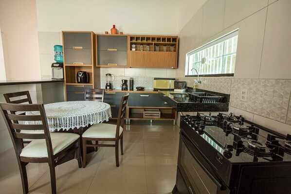 Una cocina compacta con estufa a gas, armarios de madera, microondas y un comedor con mesa y sillas.