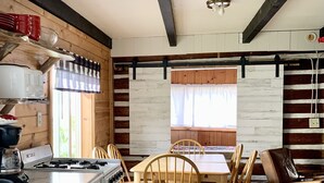 Una cocina rústica con armarios de madera, una estufa y un comedor con sillas y una mesa de madera.