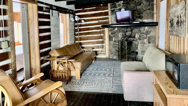 Un interior rústico con chimenea de piedra, muebles de madera y vigas a la vista.