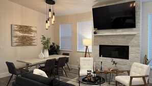 Una sala de estar moderna con chimenea, televisor de pantalla plana, comedor con mesa y sillas, y un sofá de cuero negro.