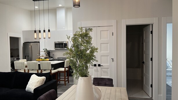 Una sala de estar moderna con un sofá negro, una mesa de centro blanca y un jarrón grande blanco con una planta.