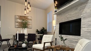 Una sala de estar moderna con chimenea, un comedor y un televisor montado en la pared.