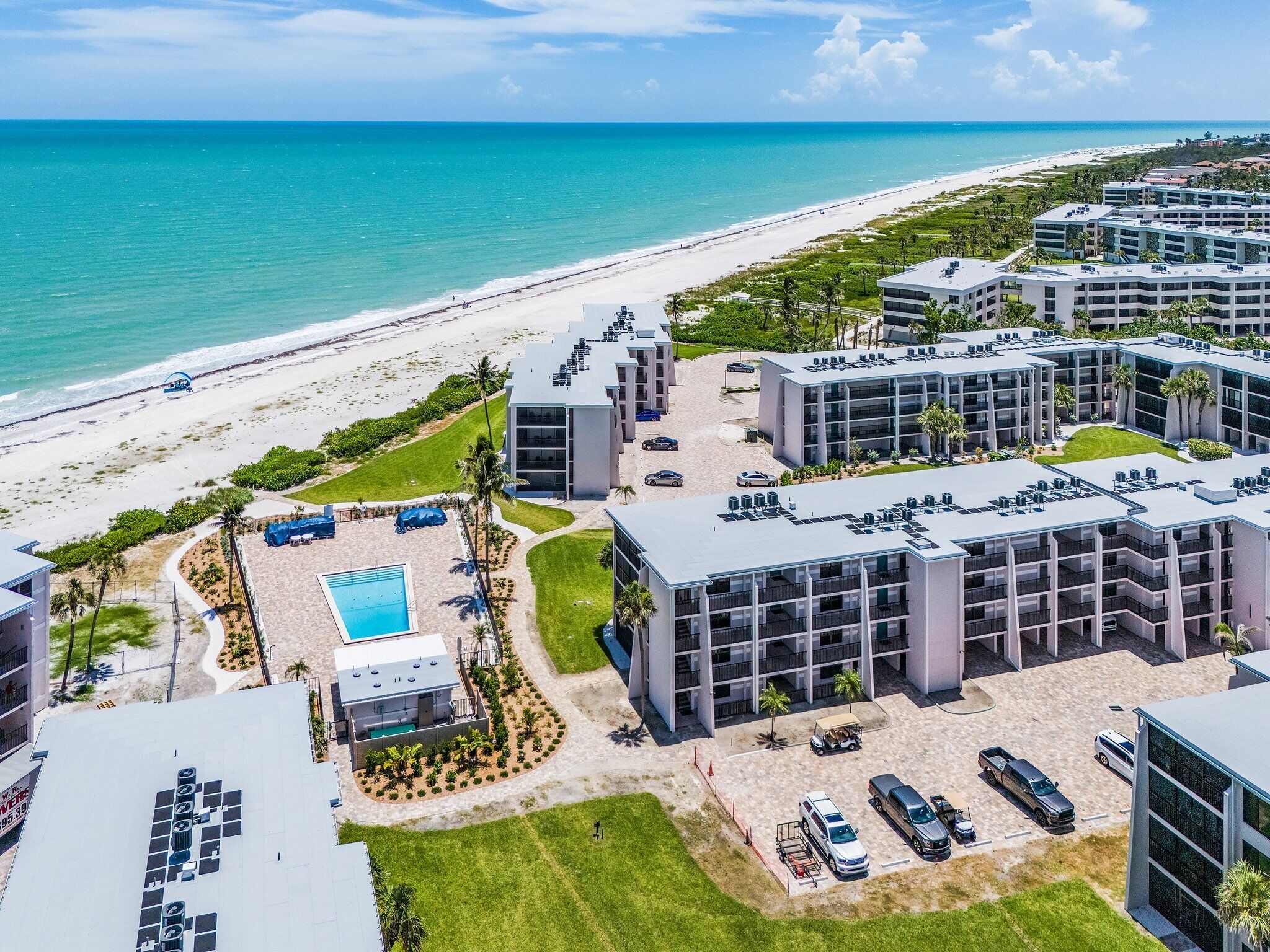 A resort with multiple buildings, a pool, and a beach view.