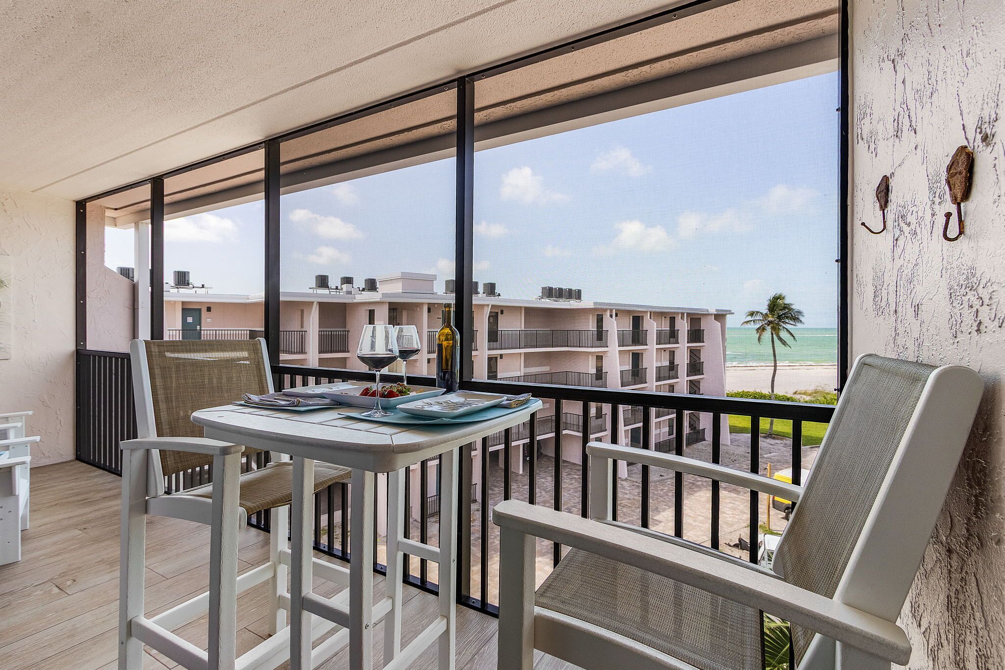 Un balcone con un tavolo apparecchiato per due, con vista sulla spiaggia e sugli edifici residenziali.