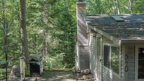 A rustic cabin with a stone chimney, a porch with a bench, and a stone pathway leading to the entrance. - Rustic Pines - Woods, Water and Nature to Relax & Unwind. (Harrison)