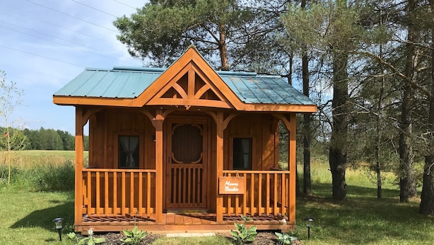 Una cabaña de madera pequeña con techo verde, un porche y un letrero que dice "Muro Rápido".
