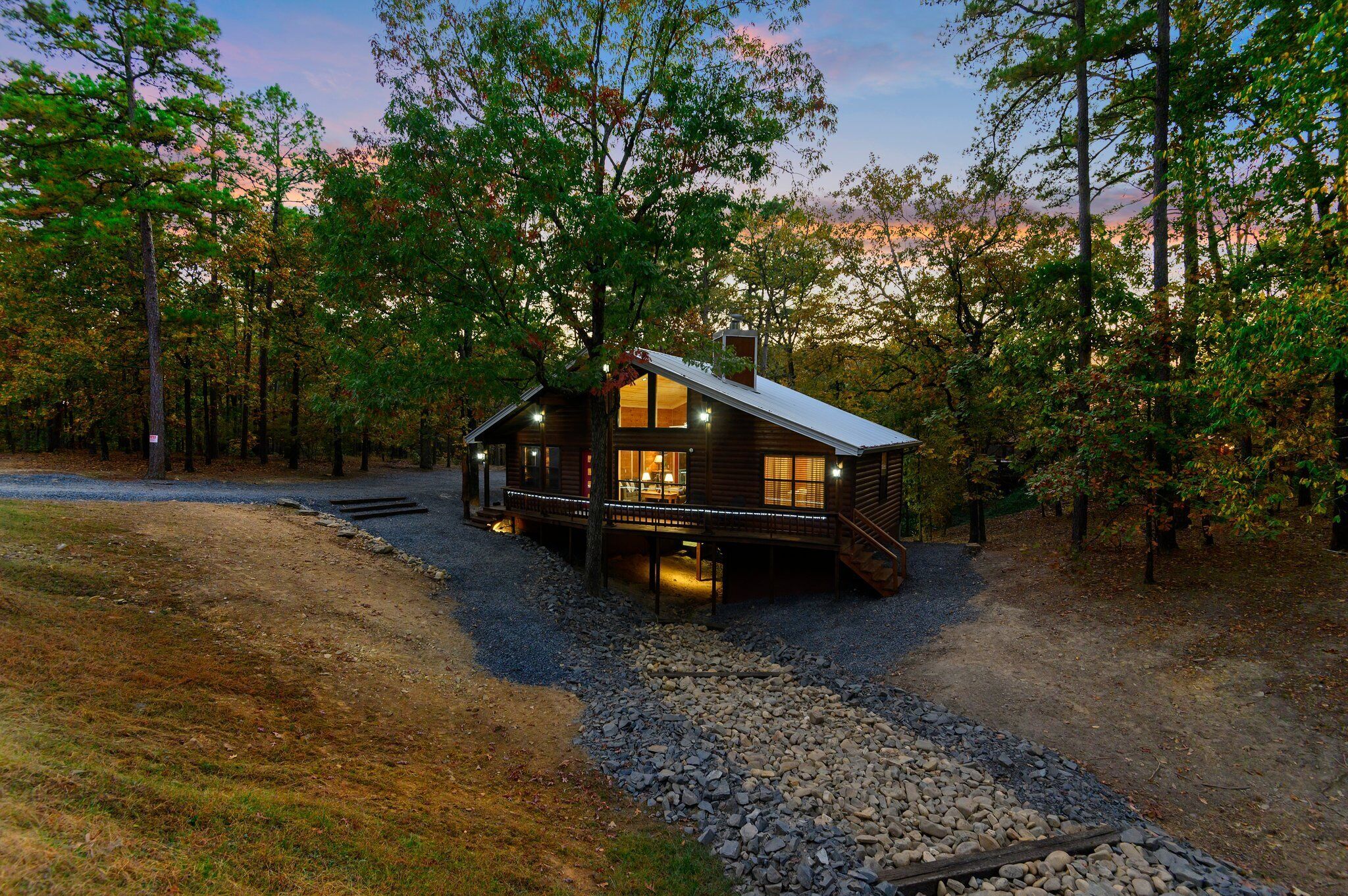Une cabane rustique avec des fondations en pierre, un revêtement extérieur en bois et une véranda.