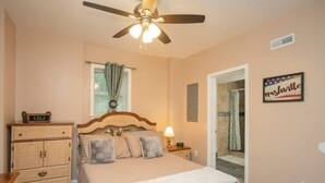 Un dormitorio con cama, mesita de noche, cómoda y ventilador de techo.