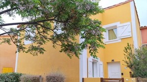 A yellow building with a gated entrance, a small window, and a door. - Superbe Pavillon Tout Confort Proche de la mer (Narbonne)