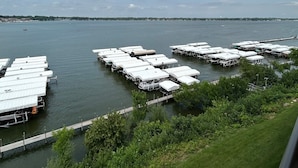 A marina with multiple docked boats, a grassy shoreline, and a clear sky. - Direct Lakeside View, 5 bed, 2.5 bath Condo at Bridges Bay (Arnolds Park)