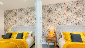 A mirrored room with two beds, floral wallpaper, and a nightstand with a lamp. - Ashfield Boutique Stays (Altrincham)