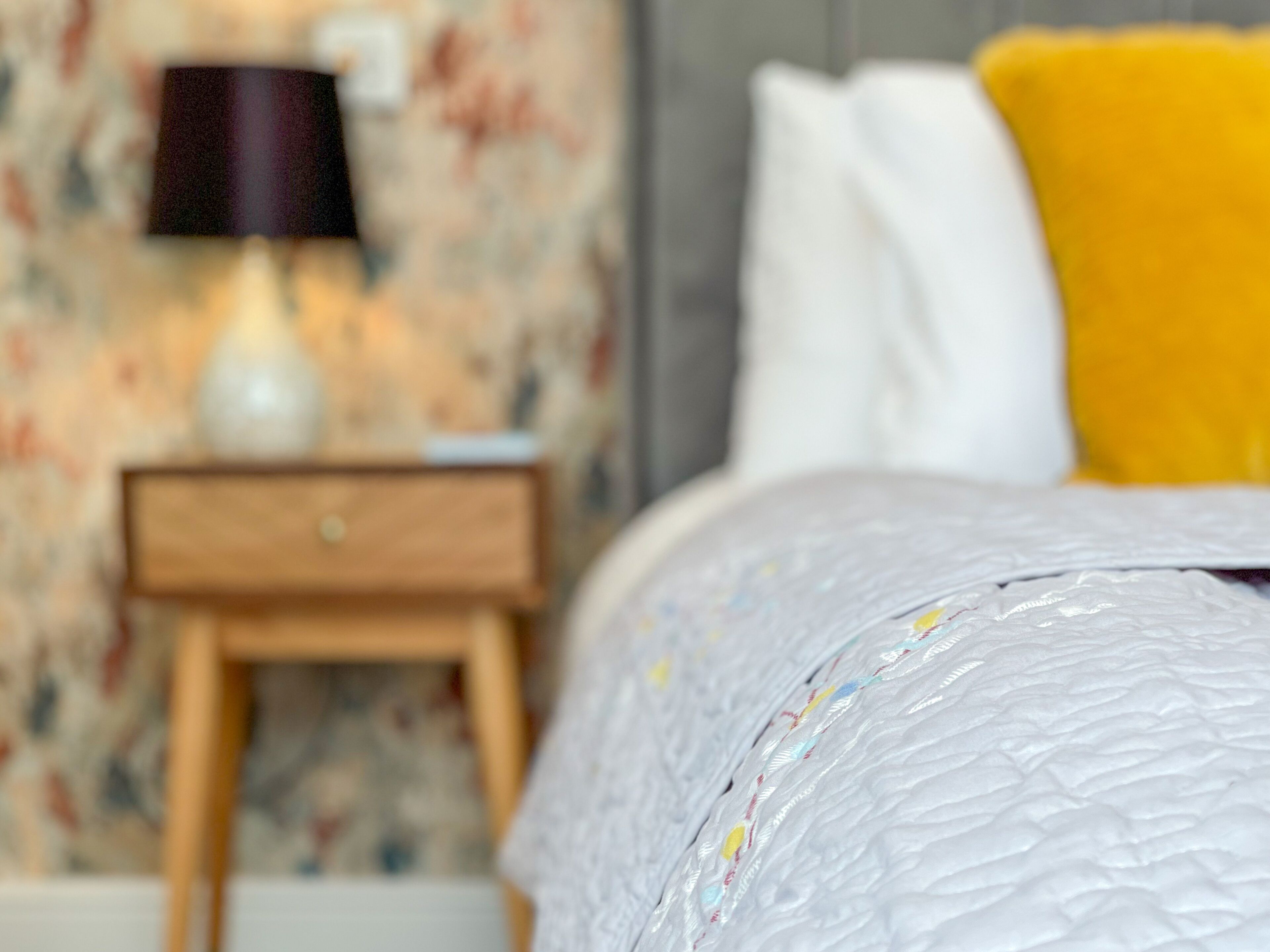 Une chambre à coucher avec un lit, une table de chevet et une lampe.