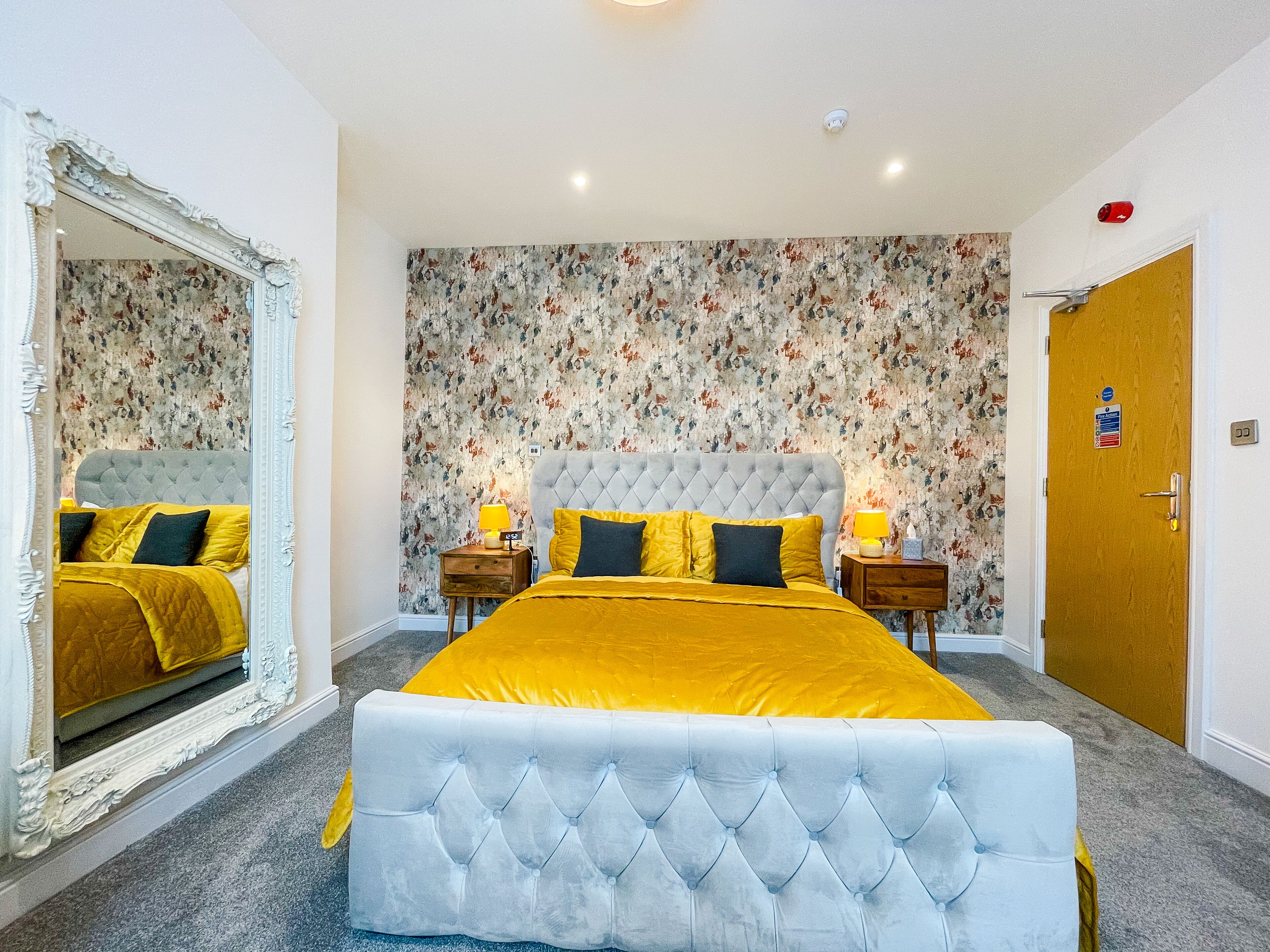 Une chambre à coucher avec un grand lit, un papier peint à motifs floraux et un miroir.