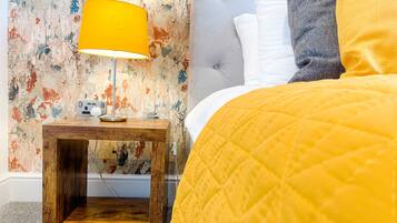 A bedroom with a bed, a nightstand with a lamp, and a wall with a textured pattern.