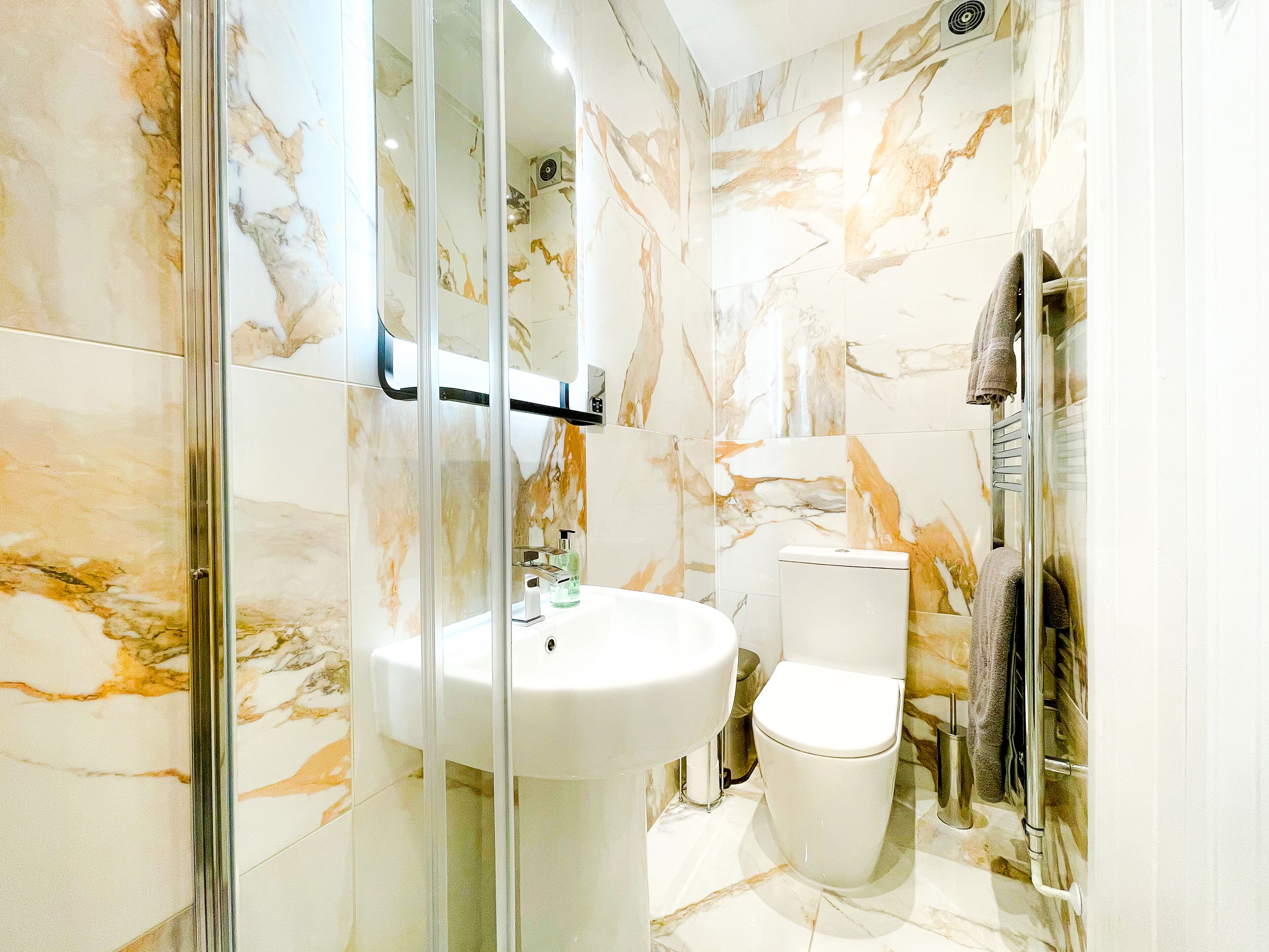 A bathroom with a glass-enclosed shower, a white sink, and a toilet.