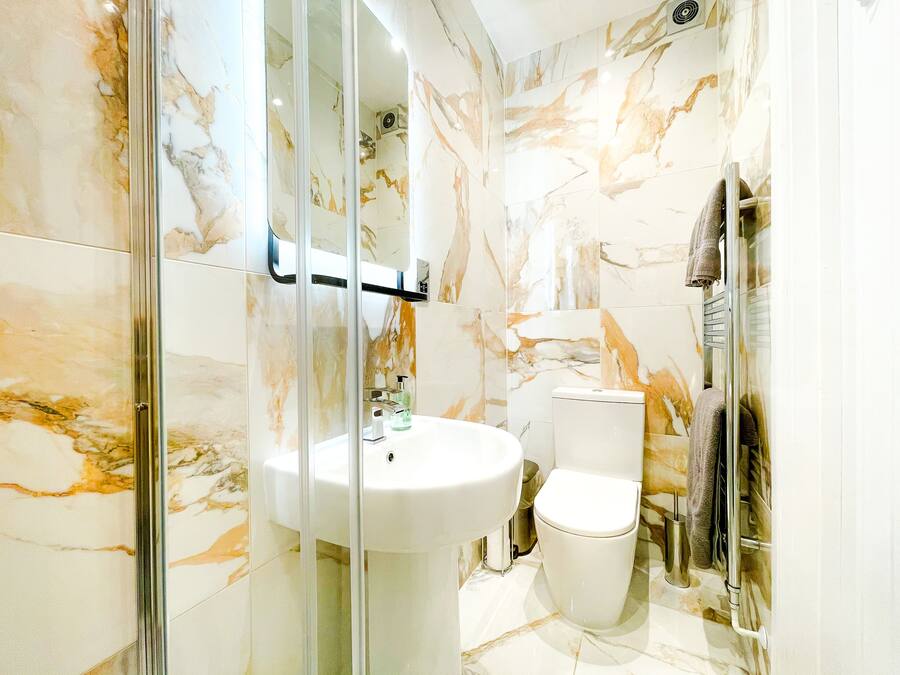 A bathroom with a glass-enclosed shower, a white sink, and a toilet.