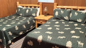 Una habitación con dos camas de madera, una ventana con persianas y adornos de madera en las paredes.