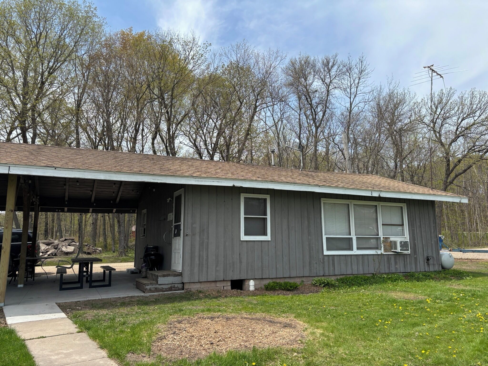 A single-story building with a covered patio, a small front porch, and a window with a white frame.
