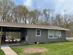 A single-story building with a covered patio, a small front porch, and a window with a white frame.