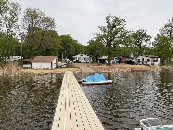 A wooden dock leading into a calm body of water with a small blue boat docked at the end.