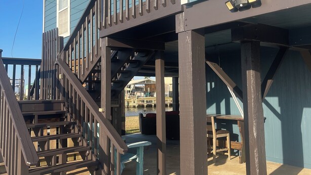 Een gebouw met twee verdiepingen en een houten trap die uitkomt op een overdekte veranda.