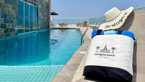 Zona de piscina con una silla de descanso, una toalla y un sombrero.
