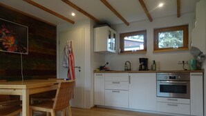 Een moderne keuken met witte kasten, een houten eettafel en een schilderij aan de muur.