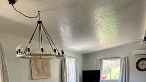 Amplia sala de estar con una mesa de comedor de madera y sillas, un televisor de pantalla plana grande, un mapa mundial en la pared y un suelo con estampado de ladrillo.
