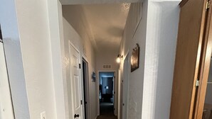 Un pasillo con paredes blancas, suelo de madera y un mueble de madera a la derecha.