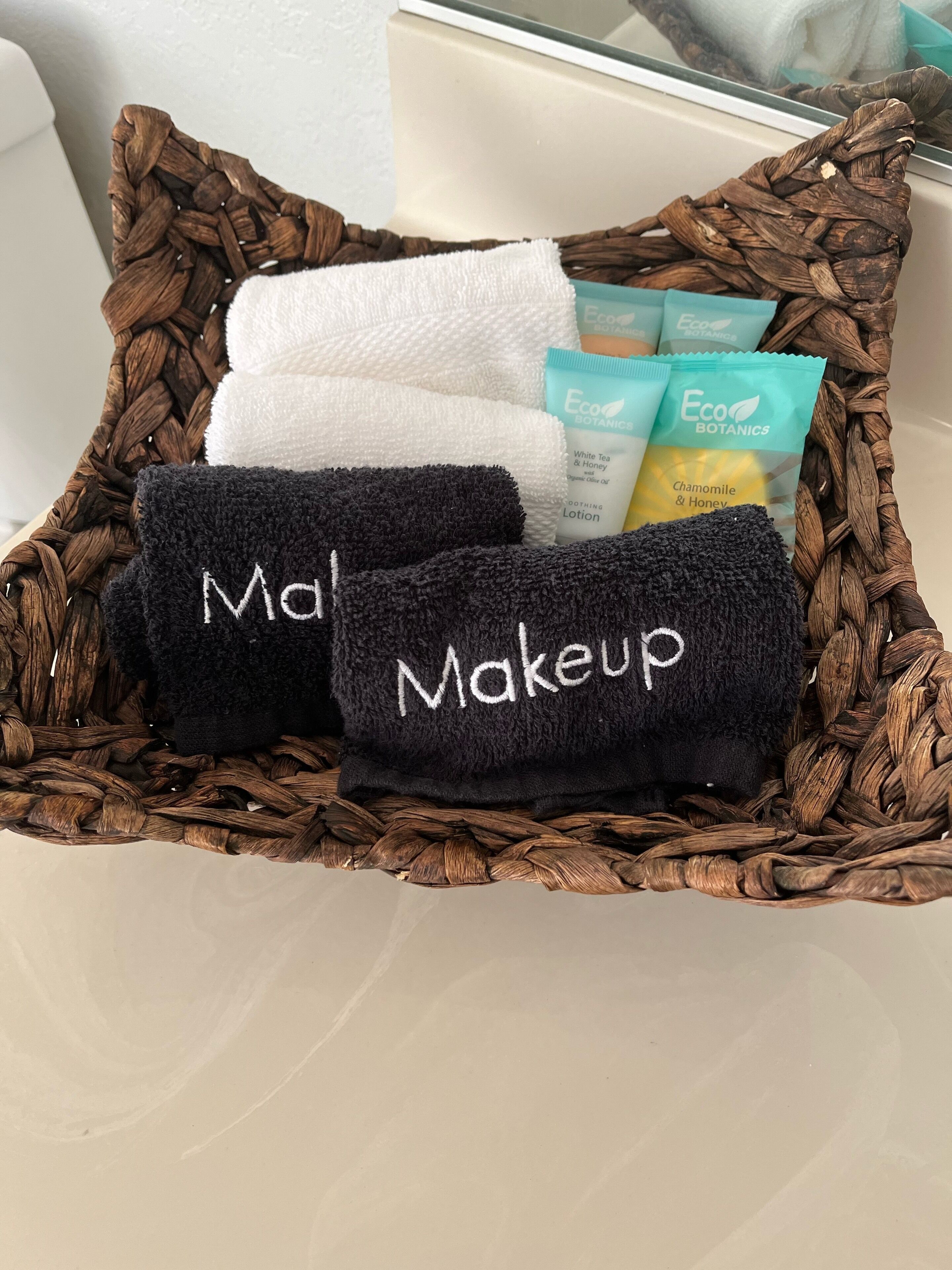 A woven basket containing towels and Eco Botanics toiletries.