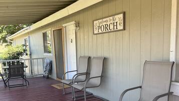 A covered porch with a red floor, two metal chairs, and a 'Welcome to The Porch' sign.