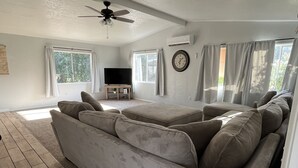 Un salón amplio con un sofá modular grande, un televisor de pantalla plana y un ventilador de techo.