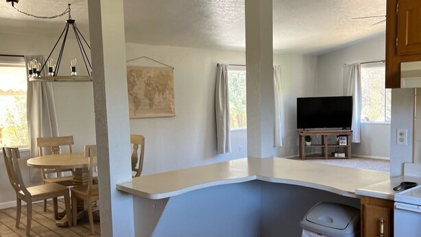 Una cocina moderna con una isla integrada, suelo de madera y un comedor con candelabro.